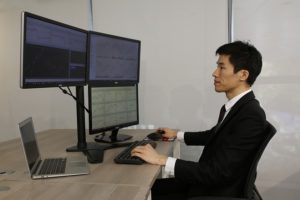 Azjatycki handlowiec obserwuje zmiany na rynku na kilku monitorach
