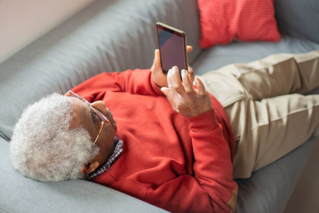 Dorosła osoba korzystająca ze smartfona na kanapie